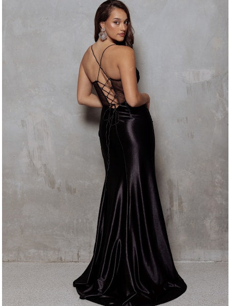 Woman wearing a black satin evening gown against a gray background